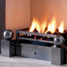 a modern fireplace with flames burning in it's center and two metal balls on each side