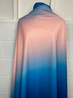 a blue and pink cape hanging on a wall