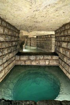 an underground swimming pool in the middle of a stone wall with water running through it