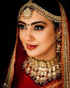 a woman in a red and gold outfit with jewelry on her face, wearing a nose ring