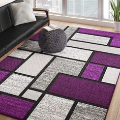 a living room with purple and black rugs on the floor next to a couch