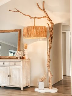 a lamp that is on top of a table next to a dresser and mirror in a room