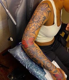 a woman sitting in a chair with tattoos on her arm