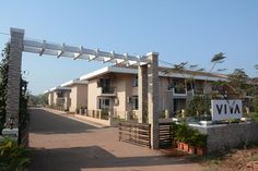 the entrance to an apartment complex with trees and plants on either side of it,