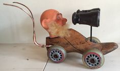 an old wooden toy car with a man's head on top and a fishing rod attached to it