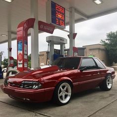 a red car parked in front of a gas station