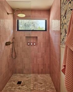 a pink tiled bathroom with a window and shower head mounted to the side of the wall