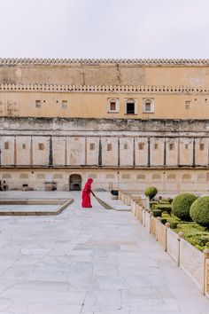 a woman in a red dress walking through a courtyard