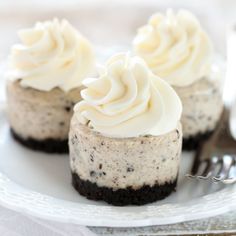 three cookies and cream cheesecakes on a white plate with silverware next to it