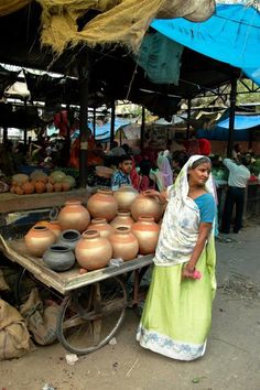 a woman standing next to a cart filled with pots