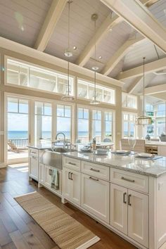 a large kitchen with white cabinets and an island in front of the window overlooking the ocean