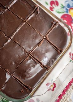 a chocolate cake sitting on top of a table next to a flowered cloth and napkin