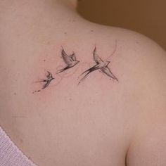 the back of a woman's shoulder with two birds flying above her left shoulder