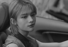 black and white photo of a young man sitting in a car with his hand on the steering wheel