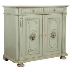 an antique style cabinet with two doors and carvings on the front, painted in pale green