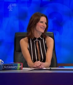 a woman sitting at a table in front of a blue screen with the words dictionary on it