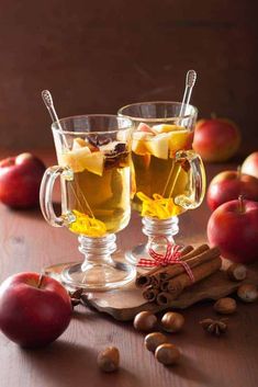 two glasses filled with apple cider and cinnamon sticks