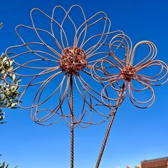 a large metal flower sculpture in front of a blue sky