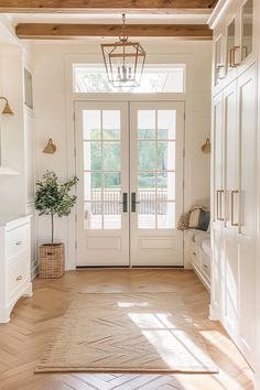 an entryway with white doors and wooden floors