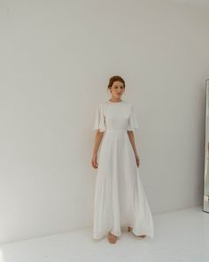 a woman is standing in front of a mirror wearing a white dress with short sleeves