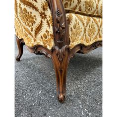 an ornately carved wooden arm chair with gold and white upholstered fabric on it