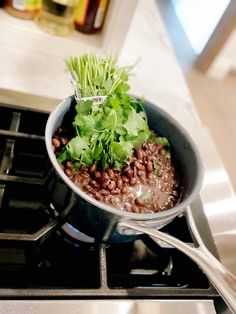 a pot filled with beans and lettuce on top of a stove