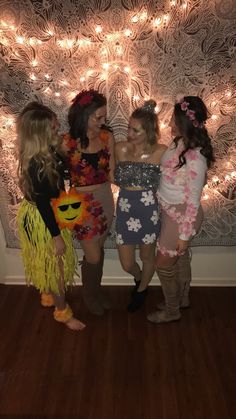 three girls standing next to each other in front of a wall with lights on it