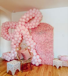 a room decorated with balloons and pink furniture in front of a large letter shaped wall