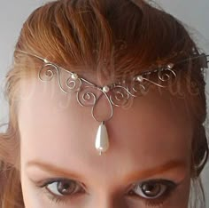 a close up of a woman wearing a head piece with pearls and wire on it