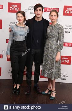 three people standing next to each other in front of a red and white wall with the word