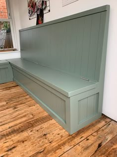 a bench sitting on top of a hard wood floor next to a wall with pictures above it