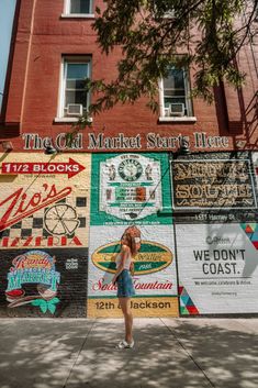 a woman standing in front of a building with many signs on it