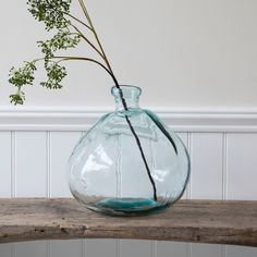 a glass vase filled with water sitting on top of a wooden table next to a white wall