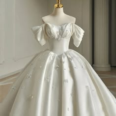 a white ball gown with puffy sleeves and beading on the bodicer