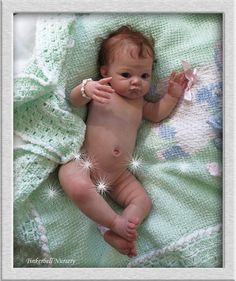 a baby laying on top of a bed under a green blanket with white sparkles