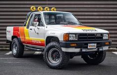 a white truck with red, yellow and orange stripes parked in front of a building