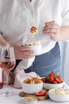 a woman is holding a spoon with food in it and strawberries on the table