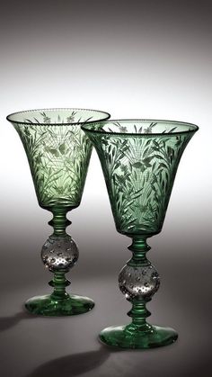 two green glass goblets sitting next to each other on a gray tablecloth