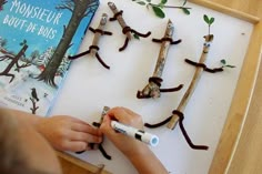 a young child is working on an art project made out of sticks and branches, with the book monsieur bout de bus