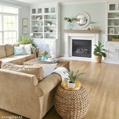 a living room filled with furniture and a fire place under a ceiling fan on top of a hard wood floor