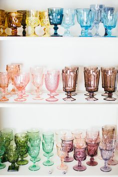 many different colored glasses lined up on shelves