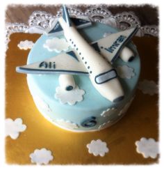 a cake decorated with an airplane and clouds on it's side is sitting on a doily