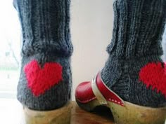 a pair of feet with red heart socks on top of each other's legs