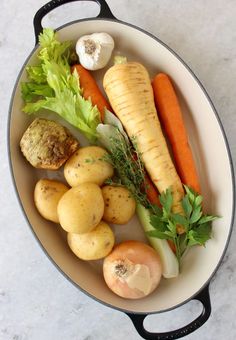 a pan filled with potatoes, carrots and other veggies on top of a table