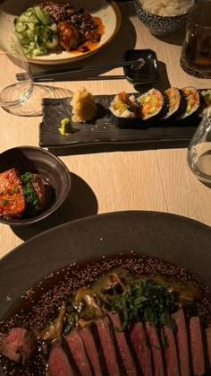 a wooden table topped with plates and bowls filled with different types of food on top of it