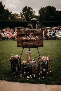 a welcome sign sitting on top of a lush green field next to a wooden sign