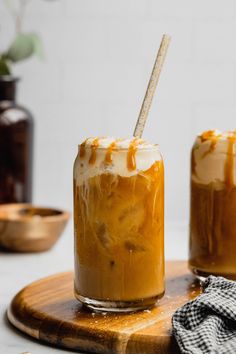 two jars filled with caramel and whipped cream on top of a wooden cutting board