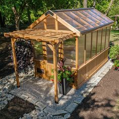 a small wooden structure in the middle of a garden with rocks and gravel around it