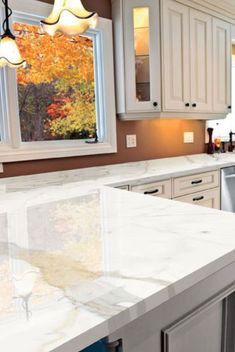 a kitchen with white cabinets and marble counter tops