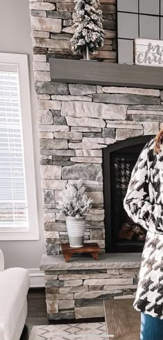 a woman standing in front of a stone fireplace